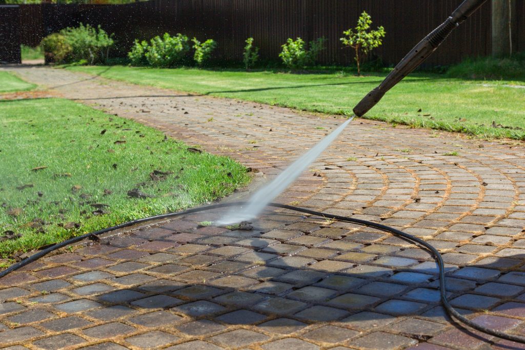 Cleaning street with high pressure power washer, washing stone garden paths